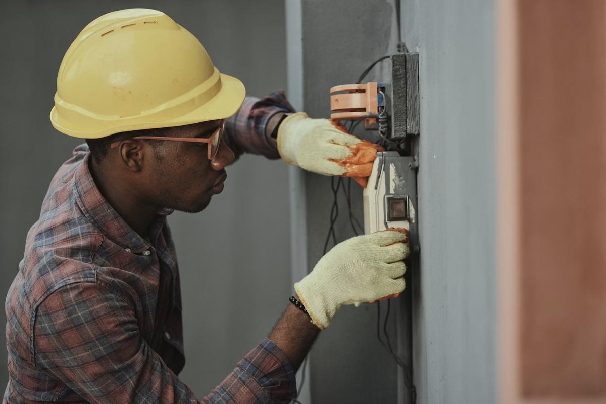 Électricien casqué intervenant sur un boîtier électrique mural